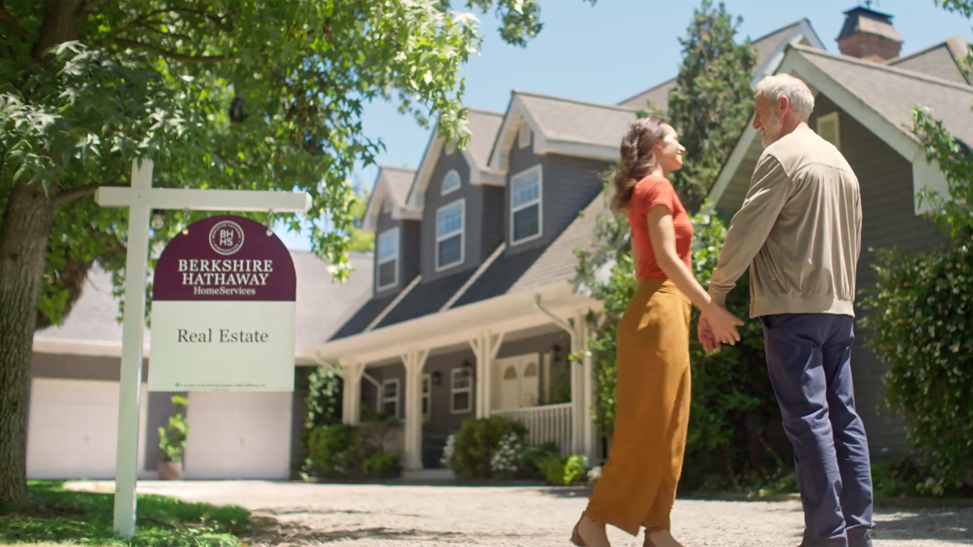 Elderly couple in front of home for sale